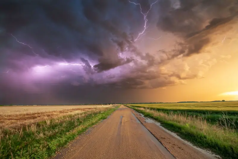 Lightning storm over a farm field and dirt road on the plains