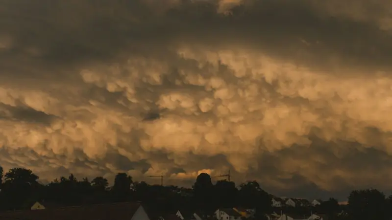 Mammatus clouds over houses at dusk after a storm